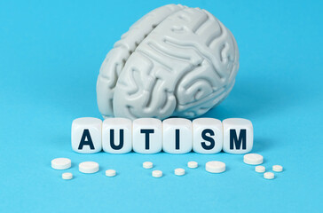 Cubes lie on the table among the pills and imitation of the brain. The text on the dice - AUTISM