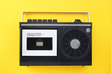 Retro outdated portable stereo boombox radio receiver with cassette recorder from circa late 70s front yellow background. Listening music concept. Vintage old style. Tape recorder.