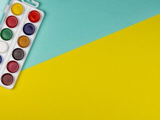 School paints for drawing on a bright yellow background. Copy space. School concept. Back to school.