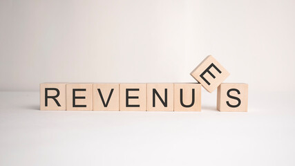 The word REVENUES is written on wooden cubes on a light background. Business concept