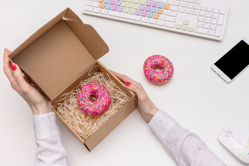 Desk in the office, businesswoman took out delicious donuts for lunch, a girl's hands with a box of donuts, top view, flat lay
