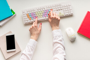 Female hands working on computer, office desk on white background, top view, flat lay