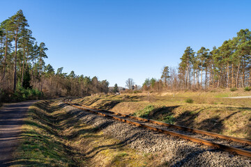 Railroad in autumn forest with clear blue sky 