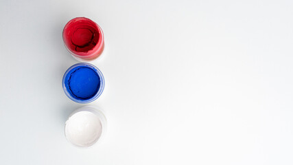 Jars of dry gouache paints, top view, close-up, white background, copy space, 16:9