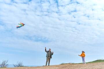 Dad and his little daughter flying a kite.