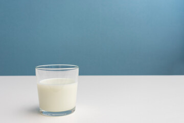 glass of fermented milk drink, blue background, cropped image, close-up, copy space