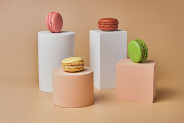 Tasty macarons on trendy geometric pedestals on a beige background