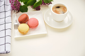 Fototapeta na wymiar Cup of coffee with macaroons on a table with flowers
