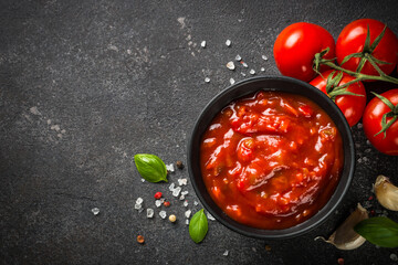 Tomato sauce in a bowl with spices, herbs and fresh tomatoes. Top view with copy space.