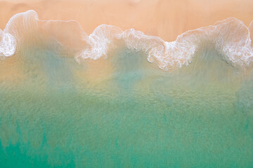 Fototapeta premium Aerial view of turquoise ocean wave reaching the coastline. Beautiful tropical beach from top view. Andaman sea in Thailand. Summer holiday vacation concept