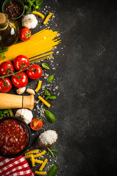 Italian food background. Pasta, olive oil, tomato sauce, spices, basil and fresh tomatoes. Top view with copy space. © nadianb