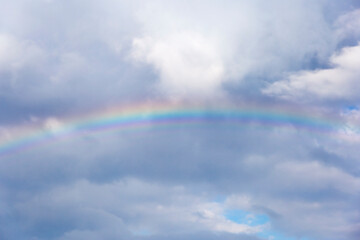 a real rainbow after a storm and warm rain, against a blue sky in the background