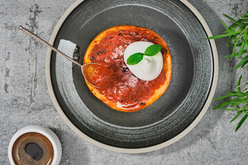 Delicious vegetarian dessert, baked or caramelized grapefruit with brown sugar and cinnamon with cream and mint leaf, set on a gray platter. Top view with copy space