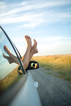 Girl sticking bare feet out of a car window. Freedom and adventure concept.