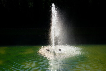Detail of the water of a fountain and its beautiful green lake, the white drops reflecting on the black background. Villa Veneta, Valsanzibio, Padua, Italy, Europe.