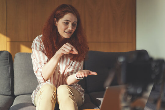 Portrair of successful influencer recording stream with digital camera, tripod and laptop