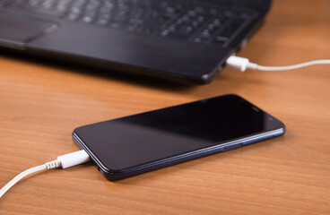Wooden background isolated charger, smartphone and computer.