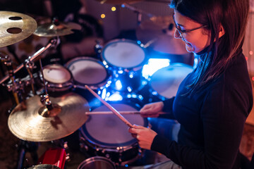 Adult caucasian woman drummer playing in dark room at home or studio - Female practice rhythm on...