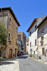 Fototapeta na wymiar Sermoneta, Italy, 05/10/2021. A street between old medieval stone buildings in the historic town.