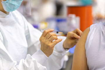 Doctor with face mask, holding syringe before make Covid-19 or coronavirus vaccine in hospital . Virus protection. COVID-2019 concept.