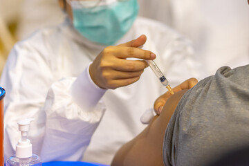 Doctor with face mask, holding syringe before make Covid-19 or coronavirus vaccine in hospital . Virus protection. COVID-2019 concept.