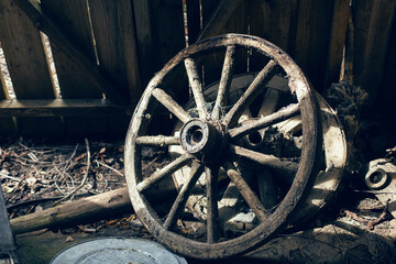 Fototapeta na wymiar wooden cart wheel stands in an old barn