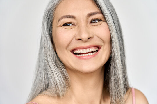 Middle aged happy mature asian woman, senior 50 year lady looking away, isolated on white closeup headshot. Ads of antiaging uv protection whitening menopause dry skincare, plastic surgery.
