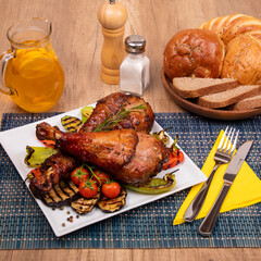 Delicious dinner, fresh roasted turkey leg served with vegetables. Bread and juice on wooden table. 