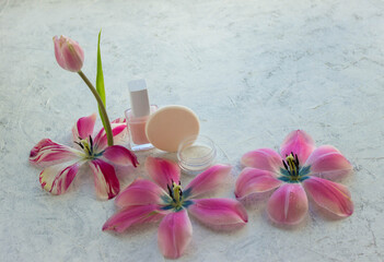 a beautiful composition of tulip flowers, sponge, cream, nail polish stand on a light gray background