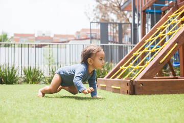 hübsches Baby krabbelt auf dem Spielplatz im Gras © topshots