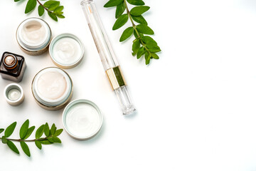 face cosmetics in gold colour, restoring mascara and sprigs of juicy greenery on a white background