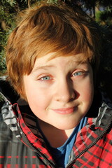 Closeup of cute preteen boy with round face blue eyes staring wide in the golden hour sun