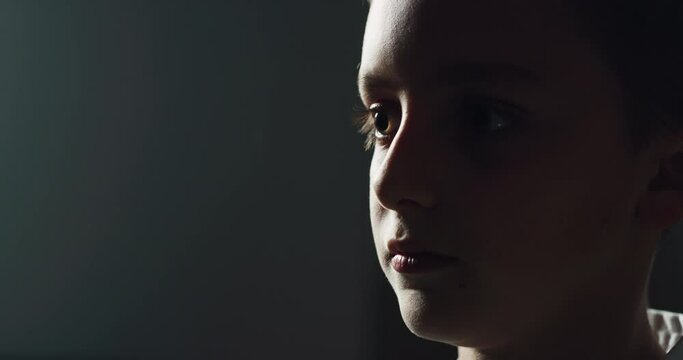 Cinematic macro shot of little boy fighter pupil with kimono concentrating before practicing Aikido in martial arts school. Concept of healthy lifestyle, sports, recreation, defense, religious beliefs