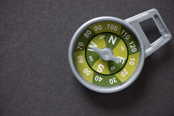 isolated grey plastic toy compass with green segments on a dark grey background