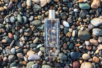 Clear perfume bottle laying on the wet stones. Idea for men cologne or perfume for brutal men,...