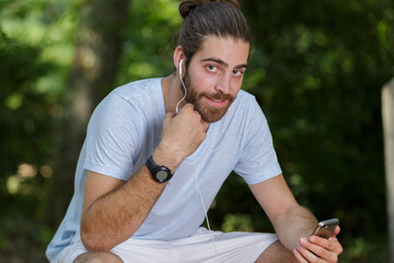 portrait of male jogger wearing headphones taking a rest