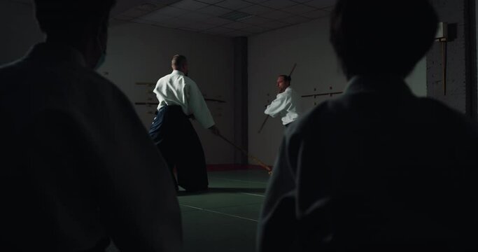 Cinematic shot of male fighters practicing Aikido training in front of audience in Japanese martial arts school. Concept of healthy lifestyle, sports,recreation, philosophy, defense, religious beliefs