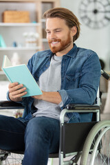 smiling man in wheelchair reading a book