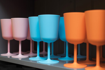 Colorful wine glasses in pink, blue and orange colors. Multicolored dishes in the kitchen bar