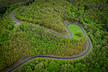Serpentine - kurvenreiche Straße - Kurven im grünen Wald - Straßenschäden - Unfallschwerpunkt - Luftaufnahme - obrazy, fototapety, plakaty
