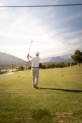 Golf player making a perfect swing on the golf course in the sunset.