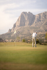 Golfer hitting ball on the green towards the hole