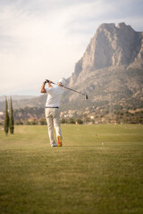 Golf player making a perfect swing on the golf course in the sunset.