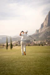 Poster Golf player making a perfect swing on the golf course in the sunset. © Henko Studio