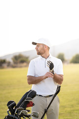 Concentrated golf player fitting his glove before swinging in the sunset.