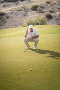 Golfer looking for the best angle to drive the ball into the hole on the green.