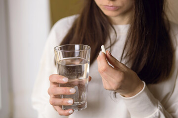 The woman is being treated, holding a glass of water and an anesthetic pill in her hand