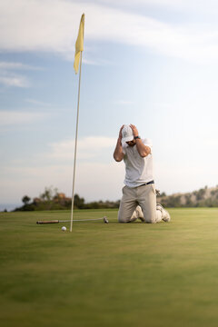 Angry golfer lamenting for missing his shot on the green a few inches from the hole.