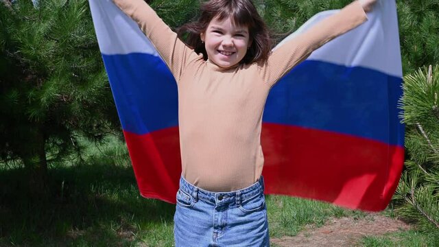 teenage girl holds the Russian national flag in the Summer sunset. Russia day on June 12. The day of the Russian flag on August 22. 4K. High quality photo