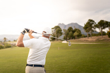 Golf player making a perfect swing on the golf course in the sunset.